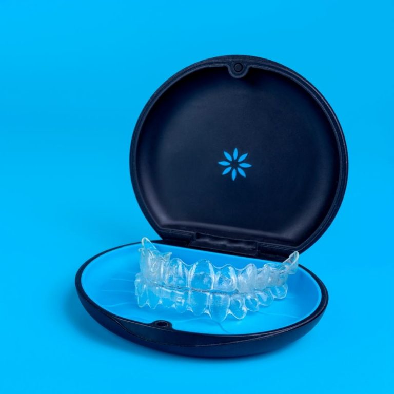 Clear teeth aligners inside a black protective carrying case on a vibrant blue background.