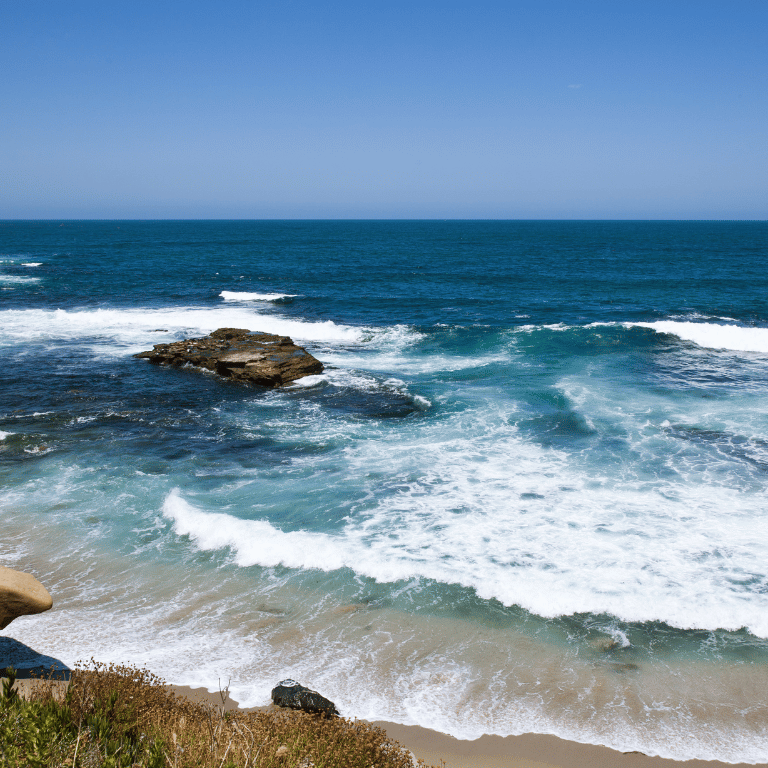 a view of a beach with waves crashing over the rocks