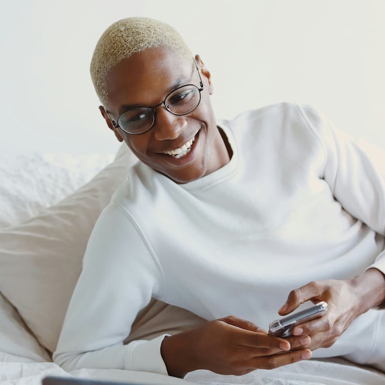Black person playing with mobile phone and smiling.