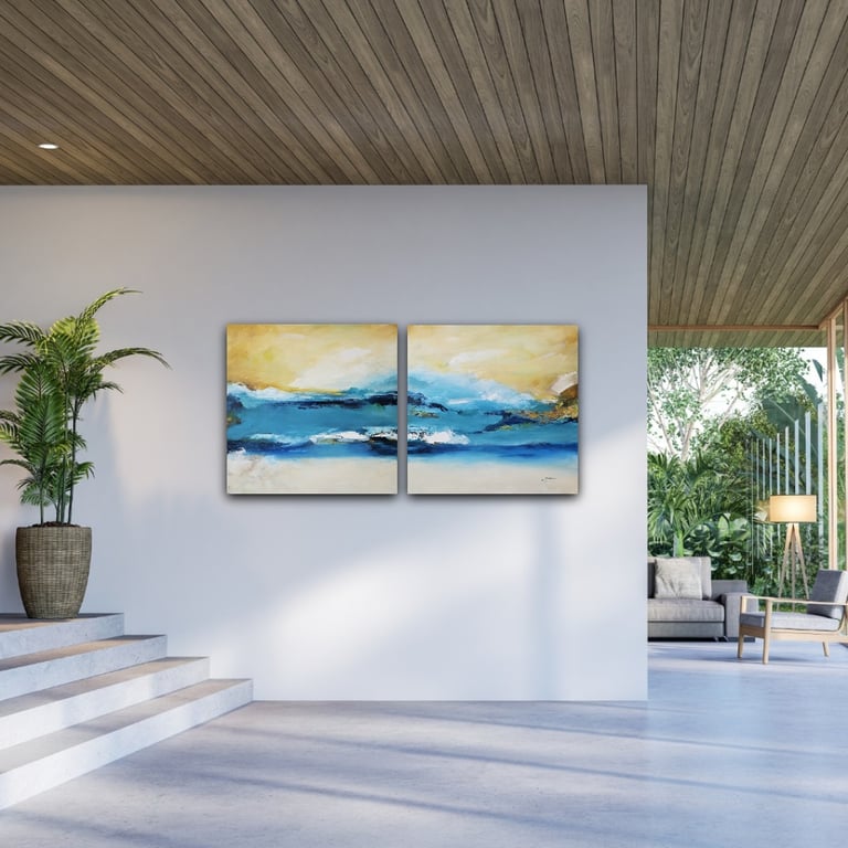 Two-piece abstract blue and gold ocean landscape art on a modern white living room wall.