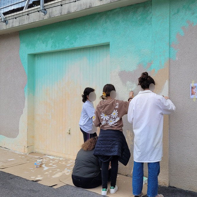 Des élèves peigent une fresque sur le mur d'une cour d'école