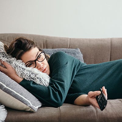 femme allongé tient une telecommande