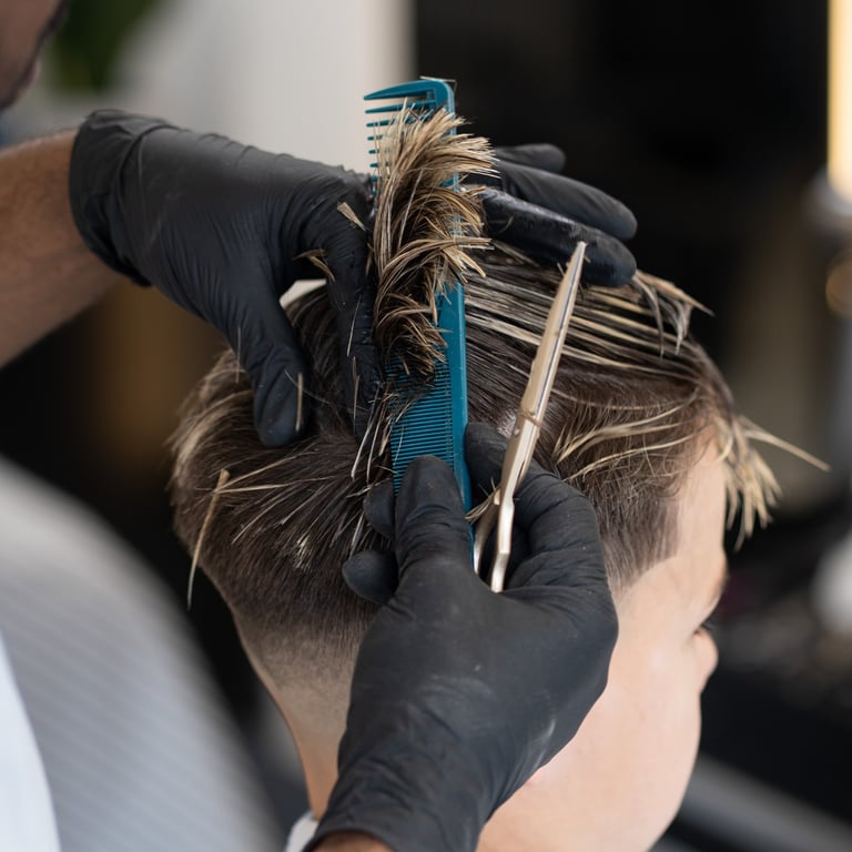 Barber combing and cutting a kids hair that has blond highlights while wet.