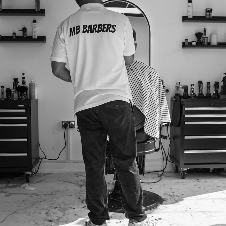 black and white image of barber with company T-shirt grooming a customer