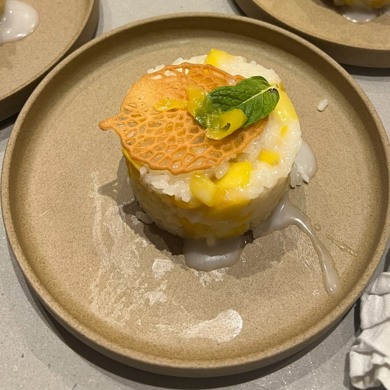 plated mango sticky rice with a coconut cream drizzle and a leaf tuile