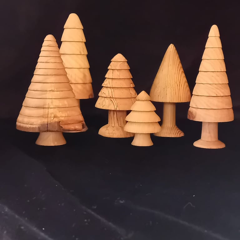 A group of golden-coloured turned wooden trees against a black background.