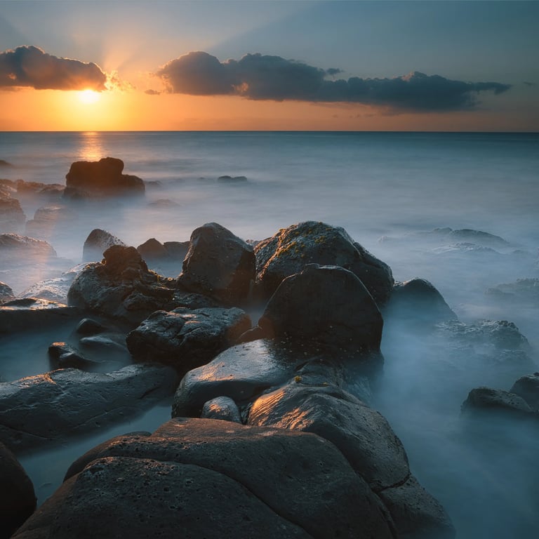 Sunset over ocean rocks in Albion, Mauritius, with long exposure waves creating misty effects