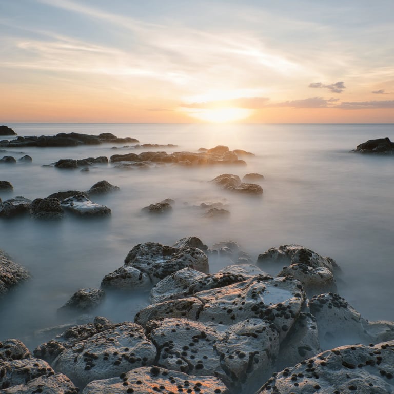 Calm ocean waters at sunset washing over rocky shores in Mauritius, with soft light illuminating the rugged coastline