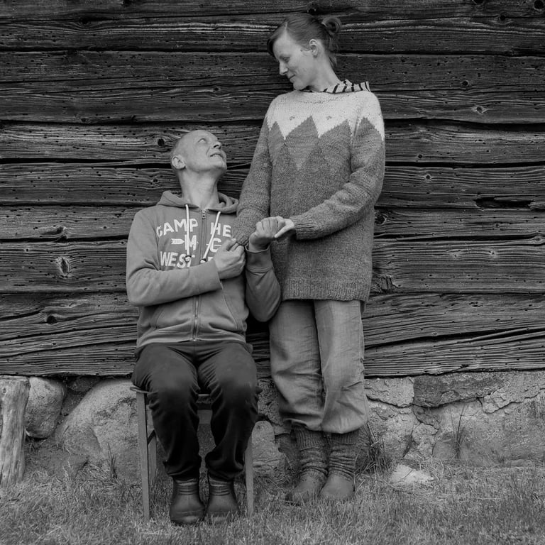 A couple seated on a chair against a wooden wall