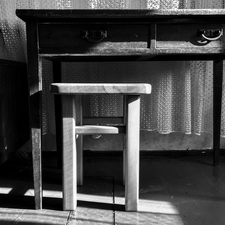 A monochrome image of a table and stool, showcasing simplicity and minimalism