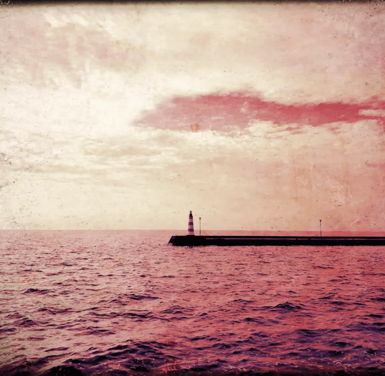 A lighthouse in the distance surrounded by red water