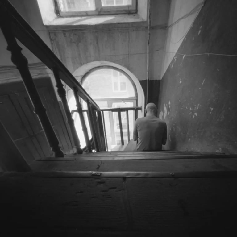 A man sitting on stairs of an old building, captured through a pinhole