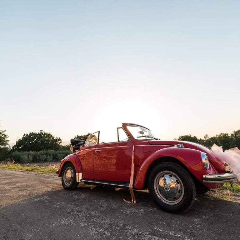 Maggiolone rosso d'epoca allestito per un matrimonio in campagna.