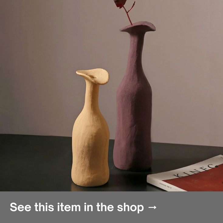Textured beige and mauve minimalist clay vases next to a magazine for Scandinavian home decor.