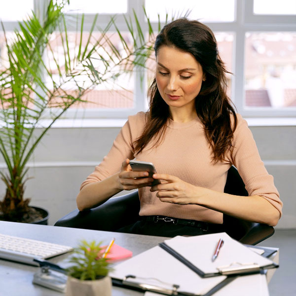 mujer enviando mensaje de texto desde la oficina