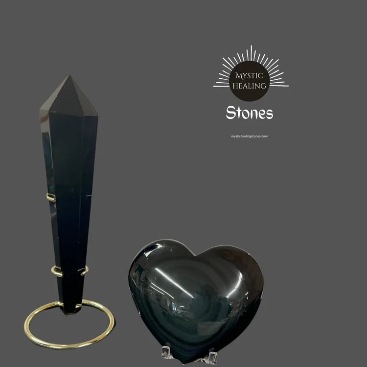 Polished black obsidian tower on a gold stand and a smooth heart-shaped healing stone crystal.