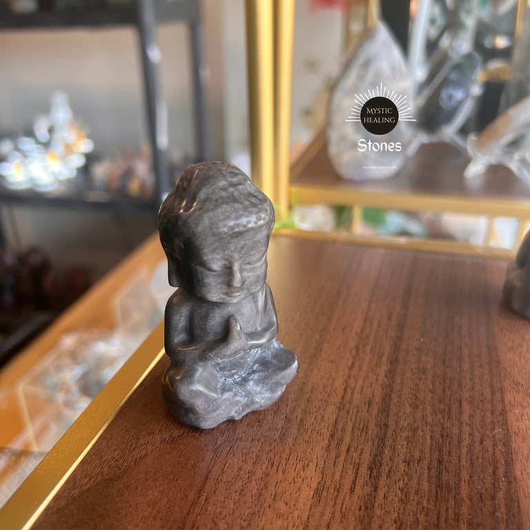 Smoky Obsidian Buddha statue in a meditating pose on a wooden shelf for spiritual decor.