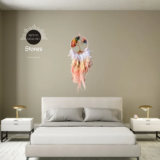 Tree of life dreamcatcher with colorful chakra stones and feathers hanging over a modern bedroom bed