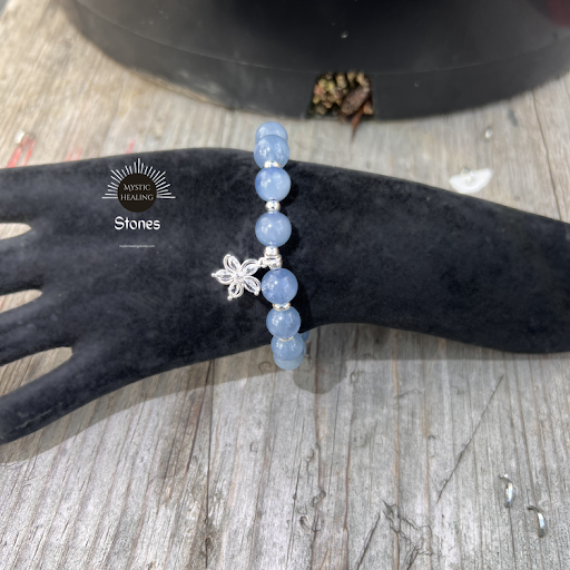 Aquamarine beaded bracelet with a silver flower charm on a black velvet display hand.