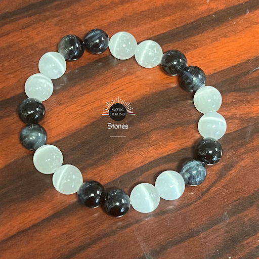 Handmade stretch bracelet featuring alternating black and white cat eye glass beads on a wood surfac