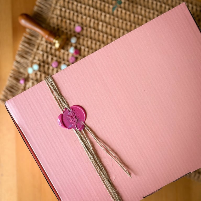 Elegant pink gift box sealed with a decorative pink flower wax stamp , ideal for festive gifting