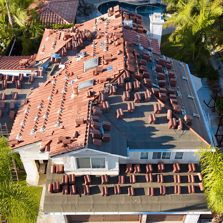 Aerial view of residential roof replacement with tiles removed and neatly stacked on the roof