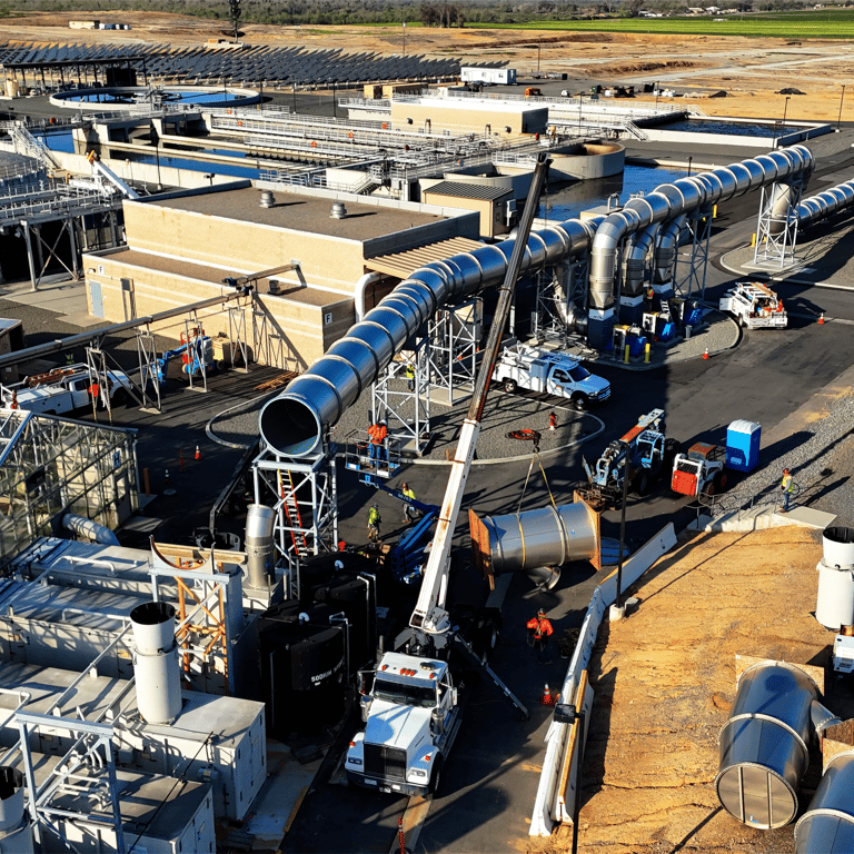 Aerial view of active industrial construction or maintenance at a large facility with workers, cranes, and heavy equipment