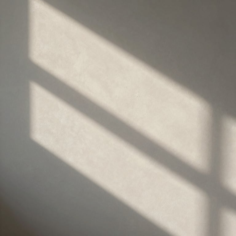 Abstract composition of shadows and light on a soft off-white textured wall, conveying tranquility.