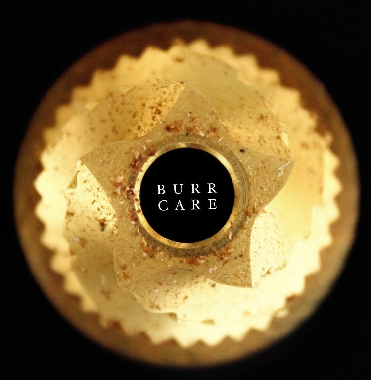 Top-down view of a coffee grinder conical burr with grounds on a black background.