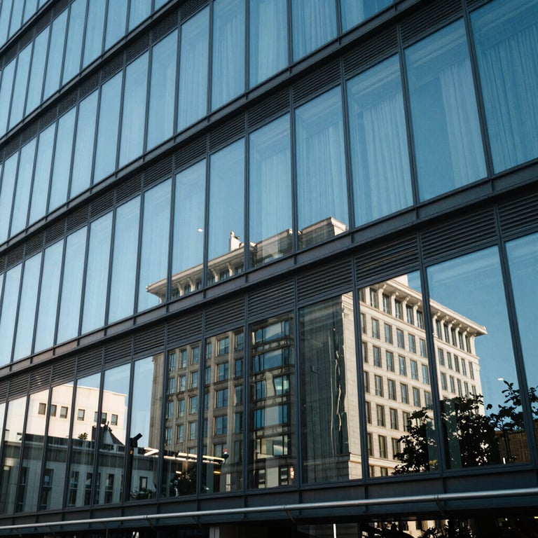Architectural detail of a modern glass office building reflecting the bright blue sky of a Western European city.