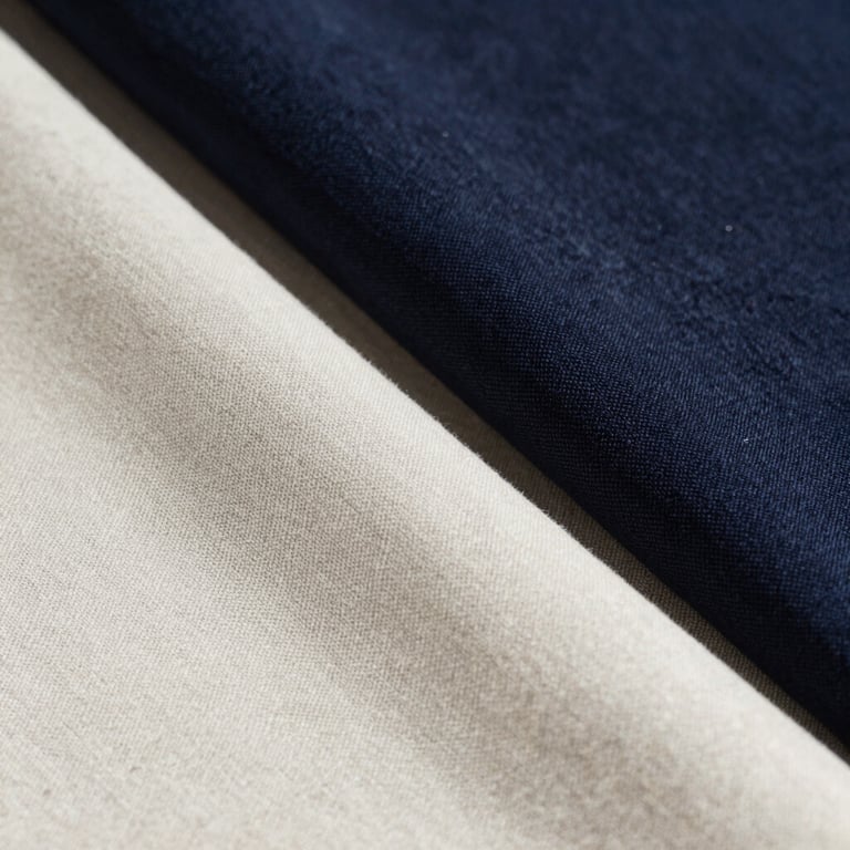 Close-up of premium linen fabric textures in varying shades of off-white and dark navy.