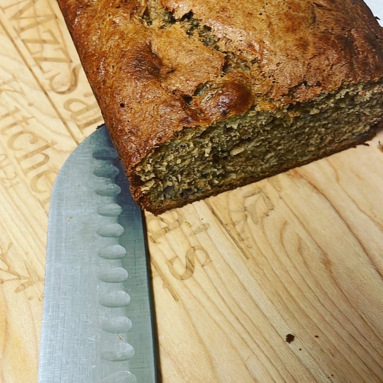 Freshly baked homemade banana bread loaf on a wooden cutting board with a slicing knife.