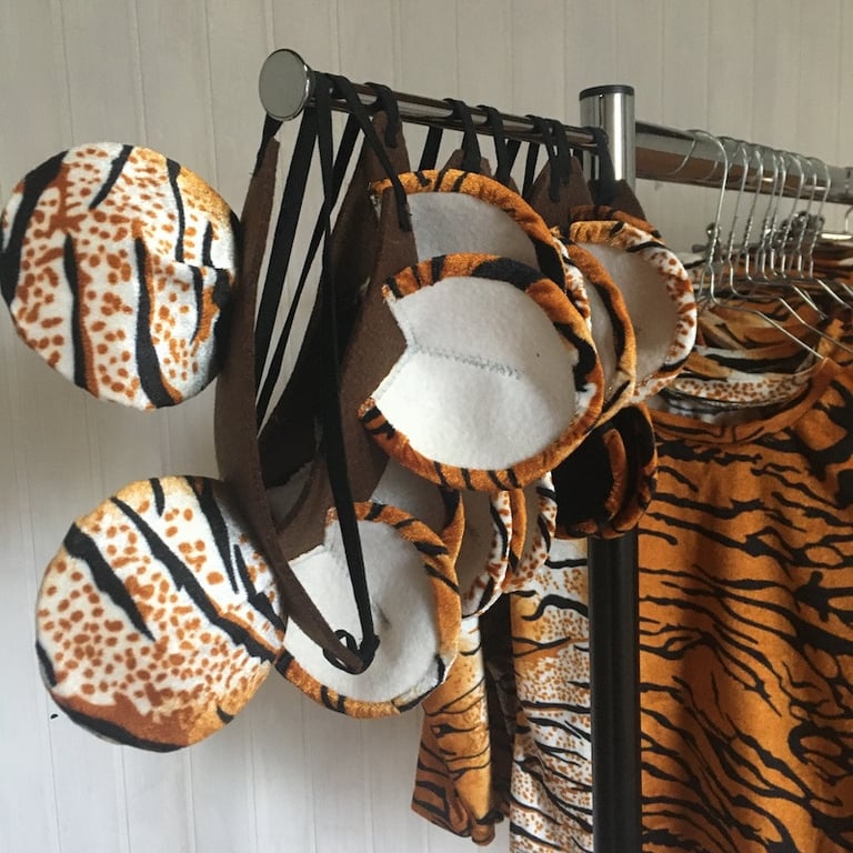 Handmade tiger ear headbands and matching animal print costumes hanging on a clothing rack.