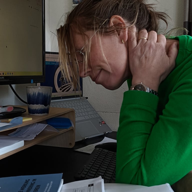 Woman experiencing neck pain while working on a laptop at her office desk.