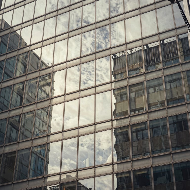 An abstract shot of sunlight reflecting off a glass building facade. Colors: warm grey and off-white.