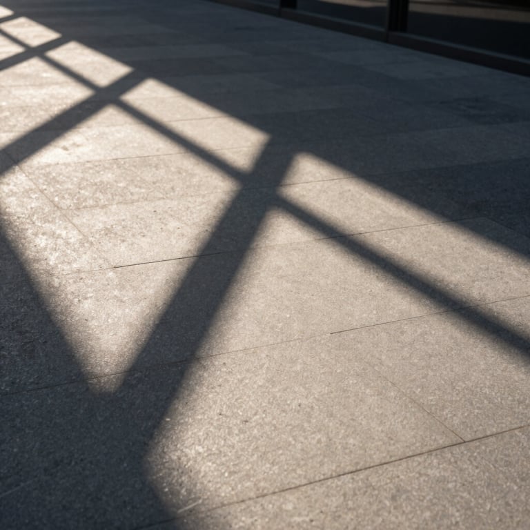 Abstract shot of modern geometric building shadows on a light slate pavement, afternoon sun.