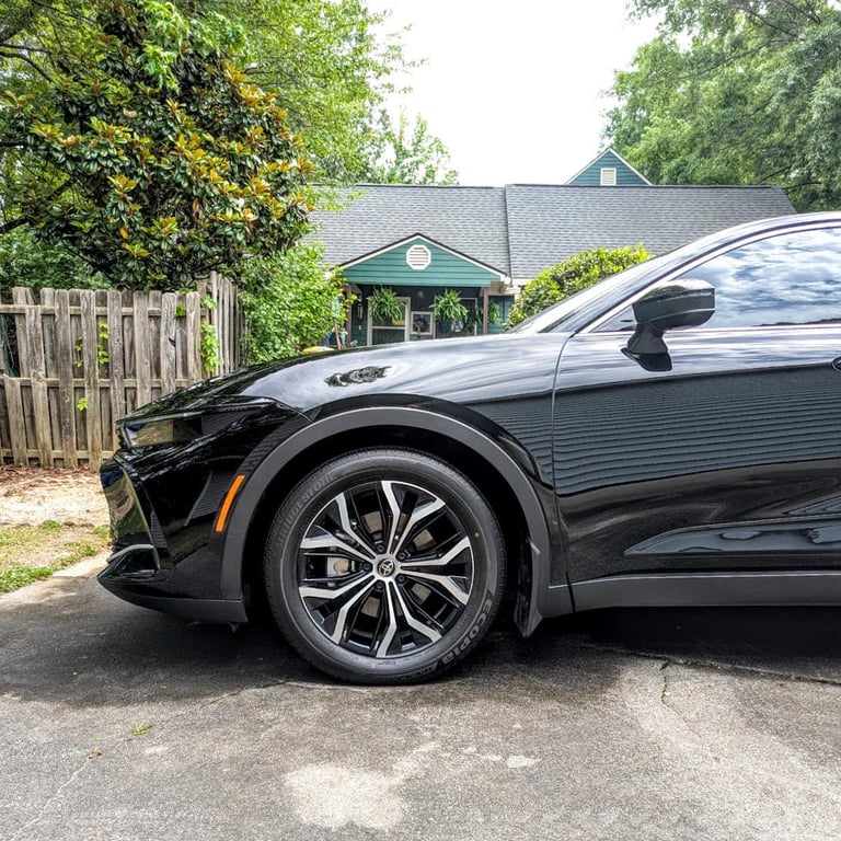 Side view of a black Toyota Crown featuring sleek alloy wheels parked in a driveway.