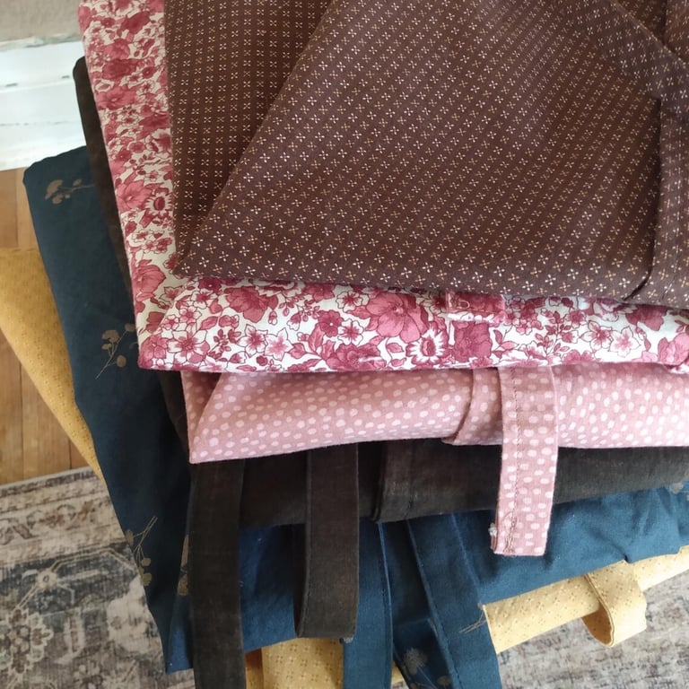 A stack of neatly folded wrap skirts made with love from assorted pretty cotton calico fabrics