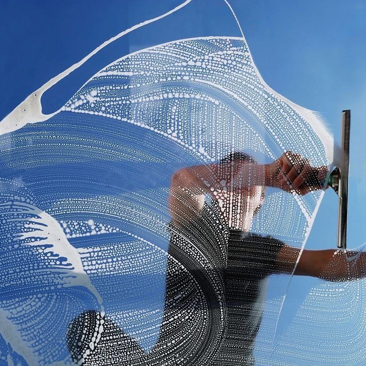 Professionnel nettoyant les vitres avec une raclette pour des fenêtres impeccables et brillantes.