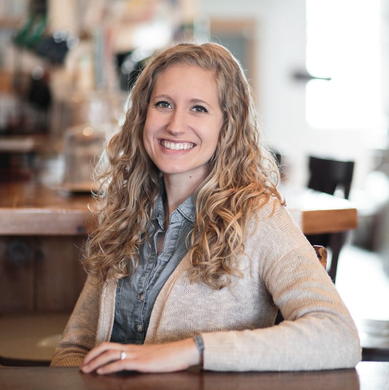 Kara smiling with arm on the table encouraging clients to contact her through the website