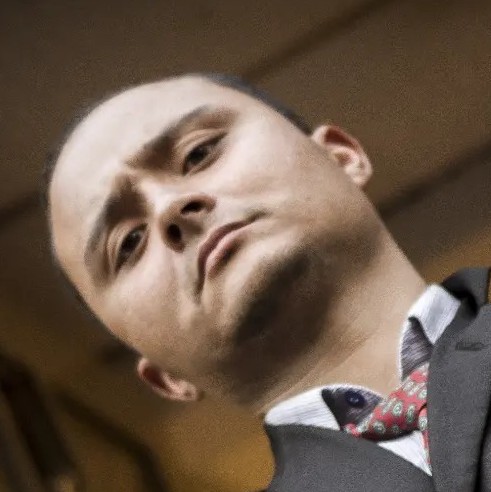 Retrato en ángulo bajo de un hombre profesional con traje gris y corbata roja estampada.