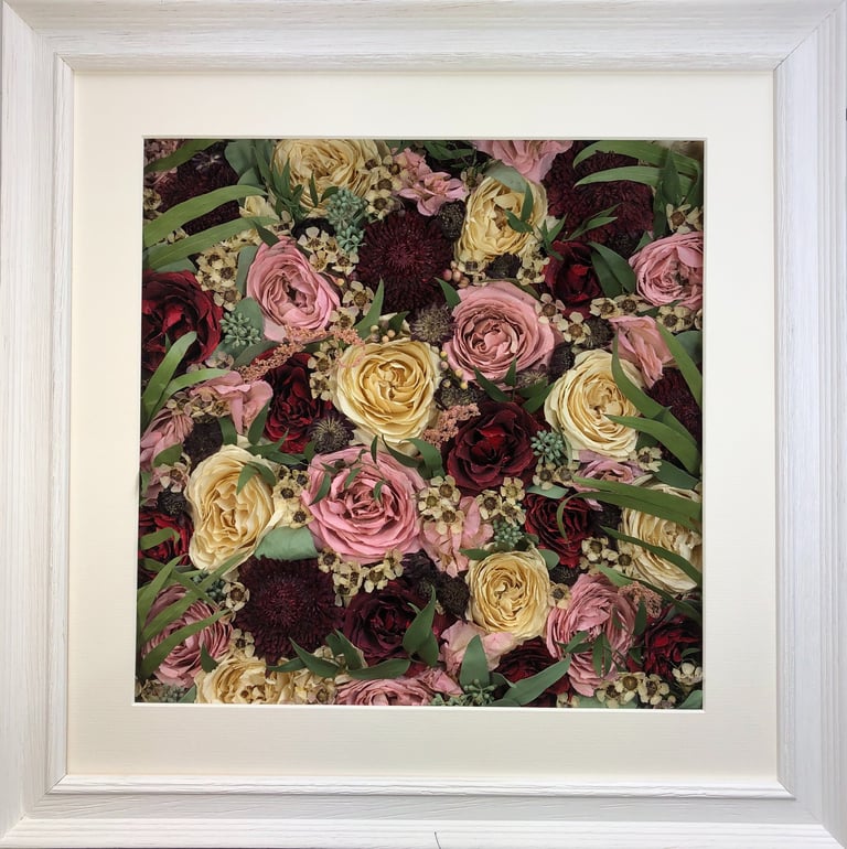 a flower wall style preserved wedding bouquet with long green leaves in a frame