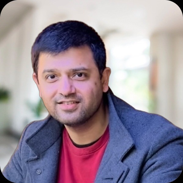 Photo of Kishore Rajendran with a grey jacket and red jumper