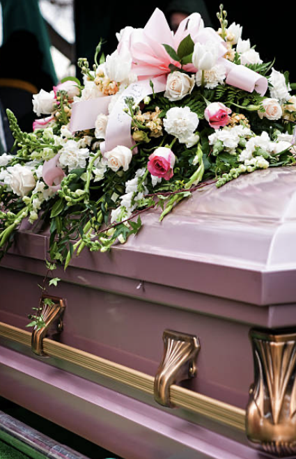 a off pink coffin with a casket sprays of cornations and roses