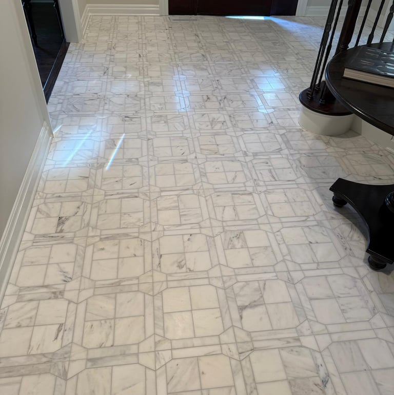 Elegant foyer entryway featuring a luxury white marble tile floor with an intricate geometric inlay pattern.