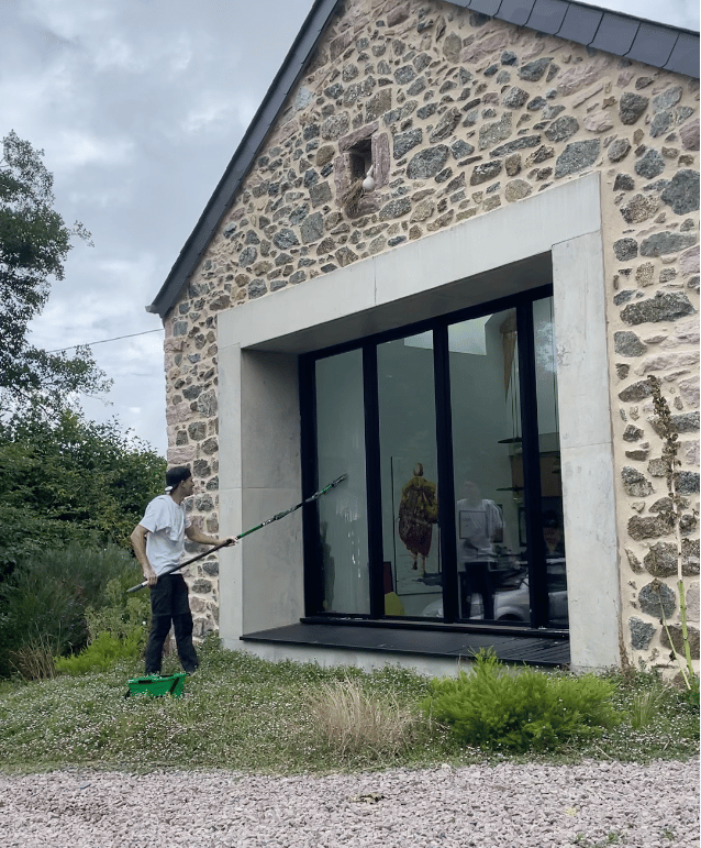 Nettoyage de grandes baies vitrées en cours avec mouilleur et raclette pour un résultat sans traces.