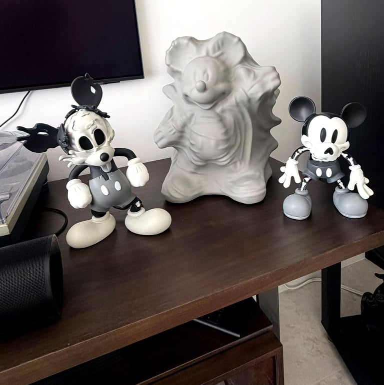 Three stylized Mickey Mouse designer vinyl art toys displayed on a dark wooden shelf.