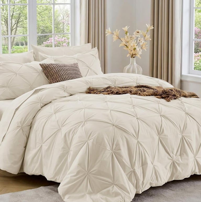 Sasttie 7-piece beige pinch pleat comforter set styled in a bright modern bedroom with neutral decor.