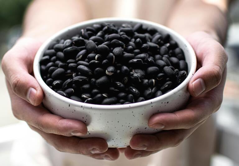 Imagen de manos sosteniendo un plato de frijoles negros