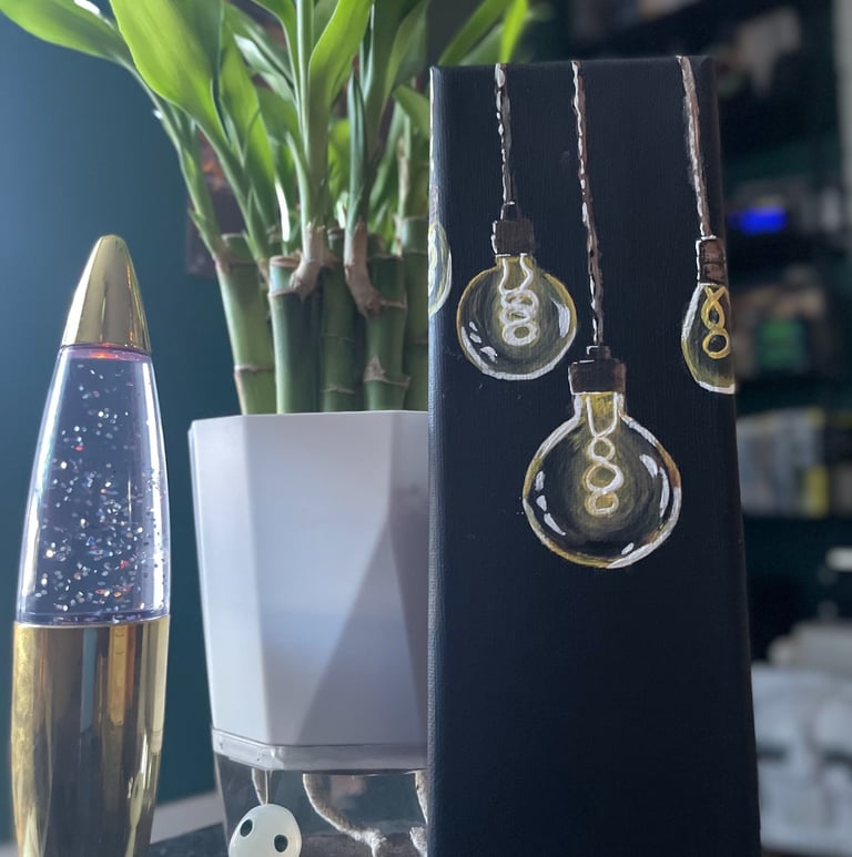 painting of lightbulbs on table with lava lamp and lucky bamboo plant